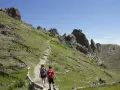 Dwoje turystów wędruje ścieżką po zboczu Gór Appalachy, wśród wypalonego lasu i zielonej trawy.