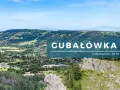 Widok z Gubałówki na panoramę Tatr. Malownicze zbocza, lasy i zabudowania tworzą piękny krajobraz.