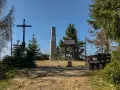 Na szczycie Turbacz, wśród **gorących szczytów**, stoi krzyż i obelisk. Wokół ławki i tablice informacyjne.