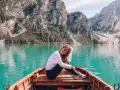 Kobieta w łodzi na turkusowym jeziorze w Dolomitach, w tle góry.