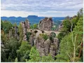 Kamienny most Bastei w Szwajcarskiej Saksonii, łączący skalne baszty pośród zielonych lasów i malowniczych gór.