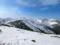 Śnieżny szlak na Grzesia w Tatrach. W oddali widać ośnieżone szczyty i ciemne pasma lasu.