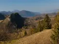 Malowniczy szlak na wysoką prowadzi przez jesienne wzgórza. W oddali widać pasmo górskie.