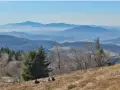 Widok na Beskid Wyspowy z malowniczymi miejscowościami w oddali. Ludzie odpoczywają na zboczu góry.