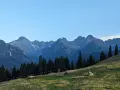 Widok na Tatry z zielonej łąki. Góry przypominają gęsią szyję, a ścieżka na zboczu sugeruje, ile schodów czeka na turystów.