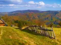 Jesienny krajobraz górski z drewnianym domkiem i potrójną palisadą.