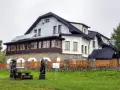 Drewniane rzeźby i ławka przed pensjonatem, idealne miejsce na odpoczynek po wędrówce po **Magurka szlaki**.