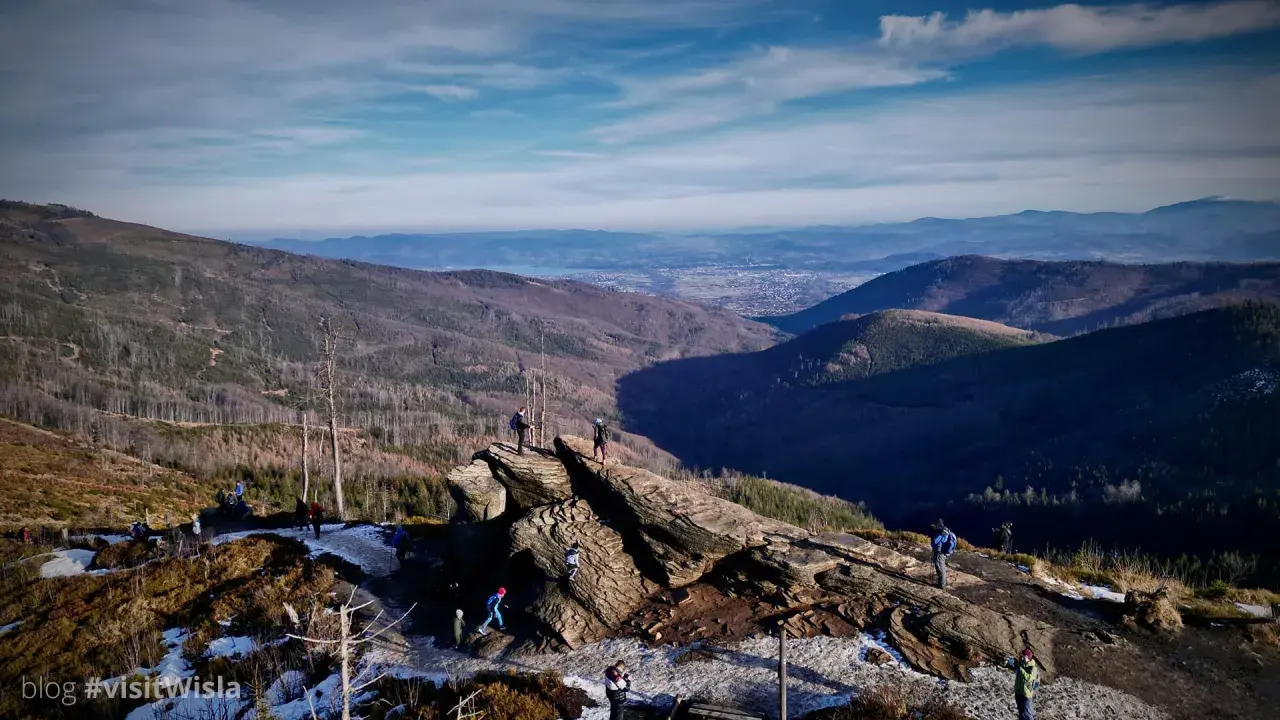 Widok na Beskidy z Wisły. Grupa turystów podziwia panoramę gór i doliny.