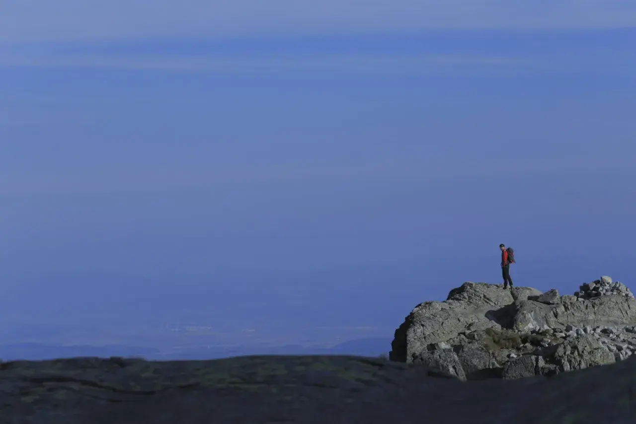 Turysta na skalistym szczycie, podziwiający widok. Tatry oferują wiele łatwych szczytów dla miłośników gór.