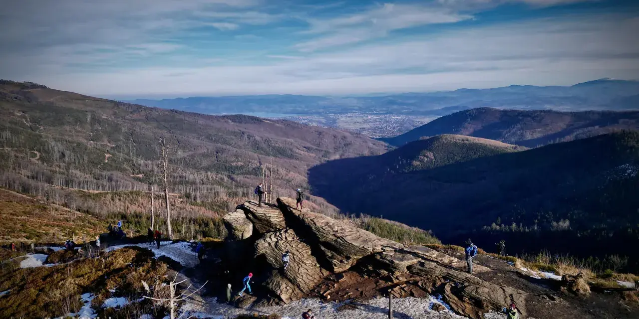 Widok na Beskidy z Wisły. Grupa turystów podziwia panoramę gór i doliny.