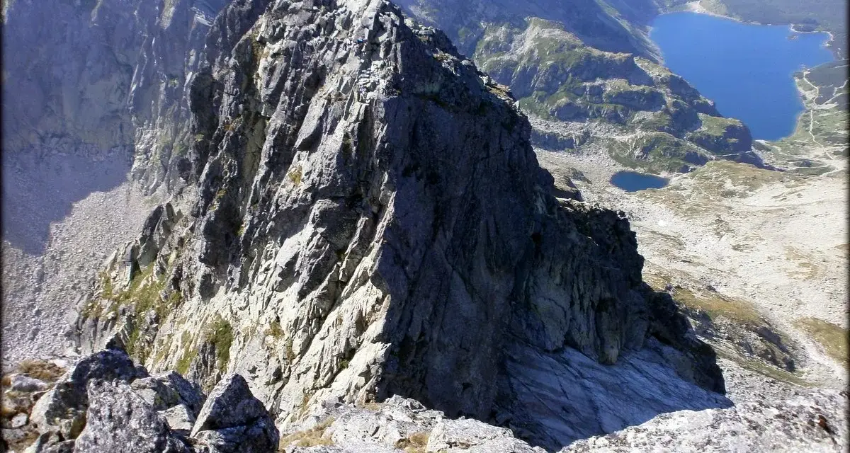 Widok z przełęczy na skraju Orlej Perci na skaliste szczyty i turkusowe jeziora w Tatrach.