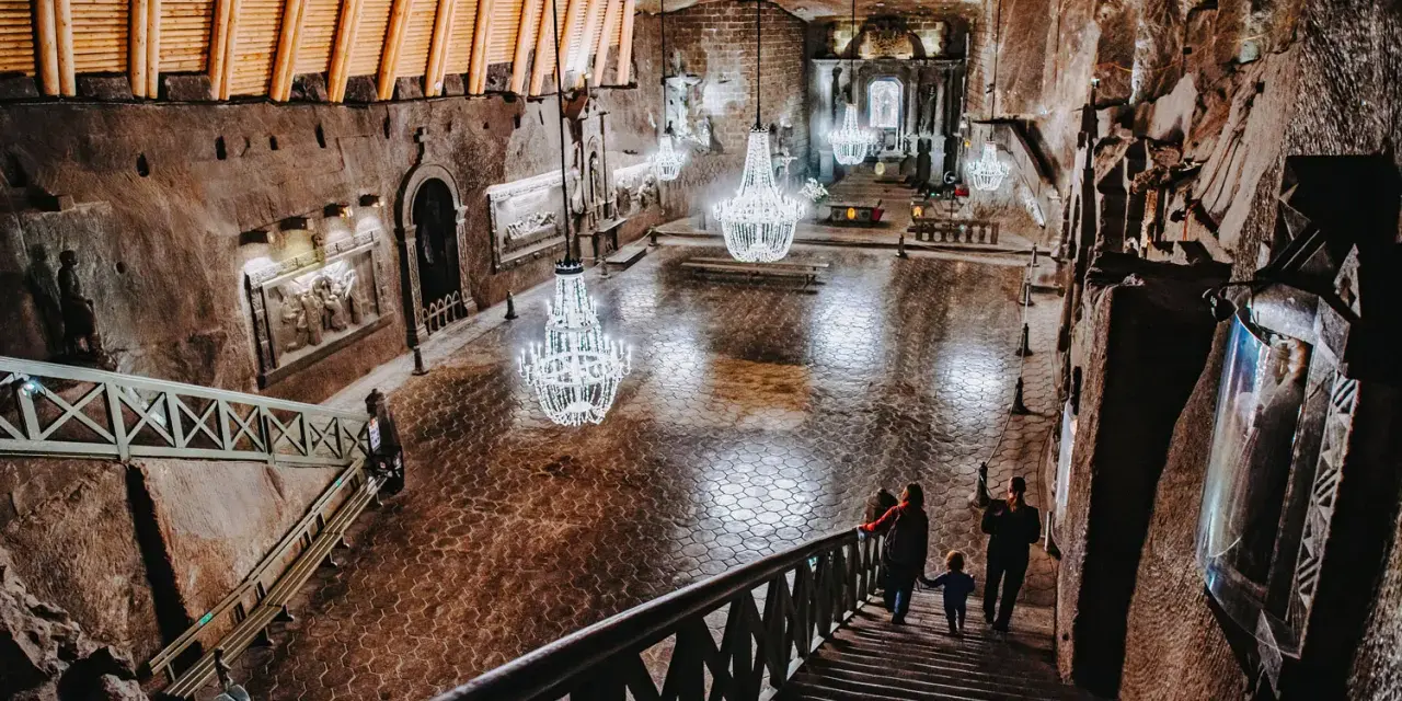 Rodzina schodzi schodami do podziemnej kaplicy w kopalni soli. Zwiedzanie Wieliczki to niezapomniane przeżycie.