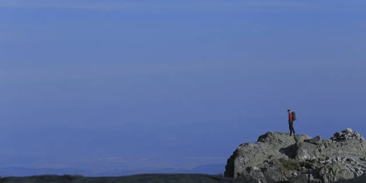 Turysta na skalistym szczycie, podziwiający widok. Tatry oferują wiele łatwych szczytów dla miłośników gór.