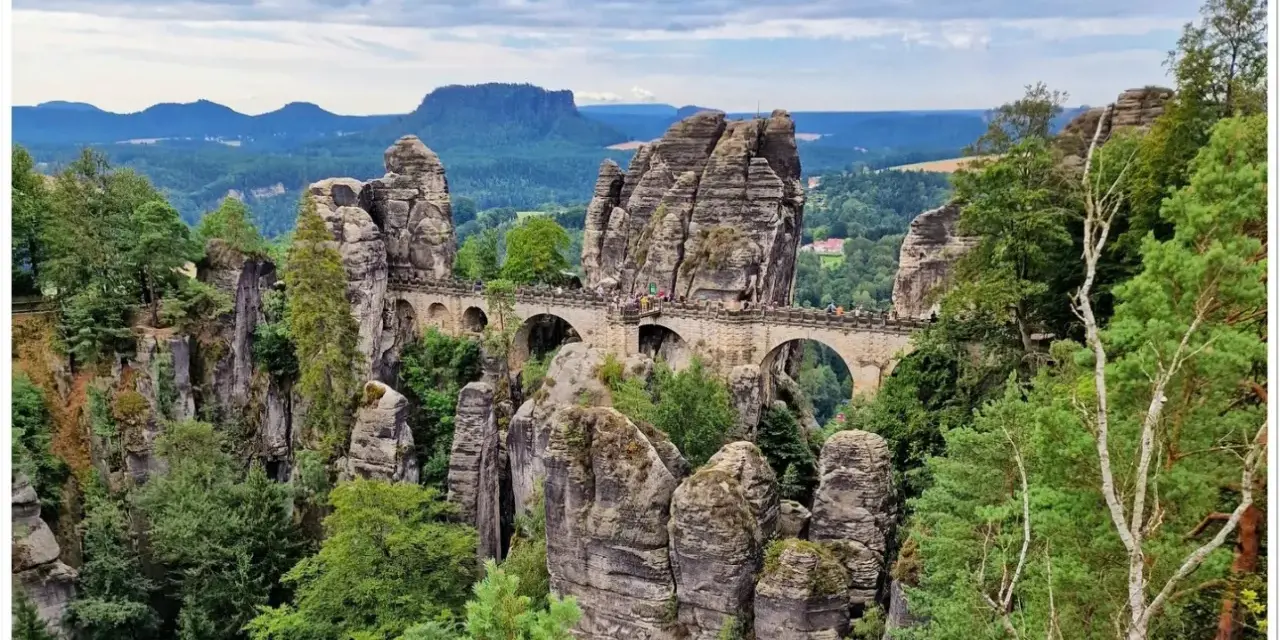 Kamienny most Bastei w Szwajcarskiej Saksonii, łączący skalne baszty pośród zielonych lasów i malowniczych gór.