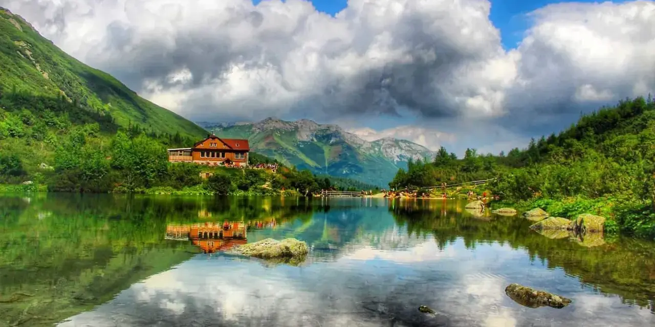 Słowackie Tatry zachwycają. Jezioro z odbiciem chatki i gór to idealne miejsce na tatry słowackie szlaki z dzieckiem.
