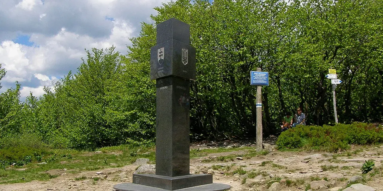 Granitowy obelisk z herbami Słowacji i Ukrainy na szczycie góry w Bieszczadach.
