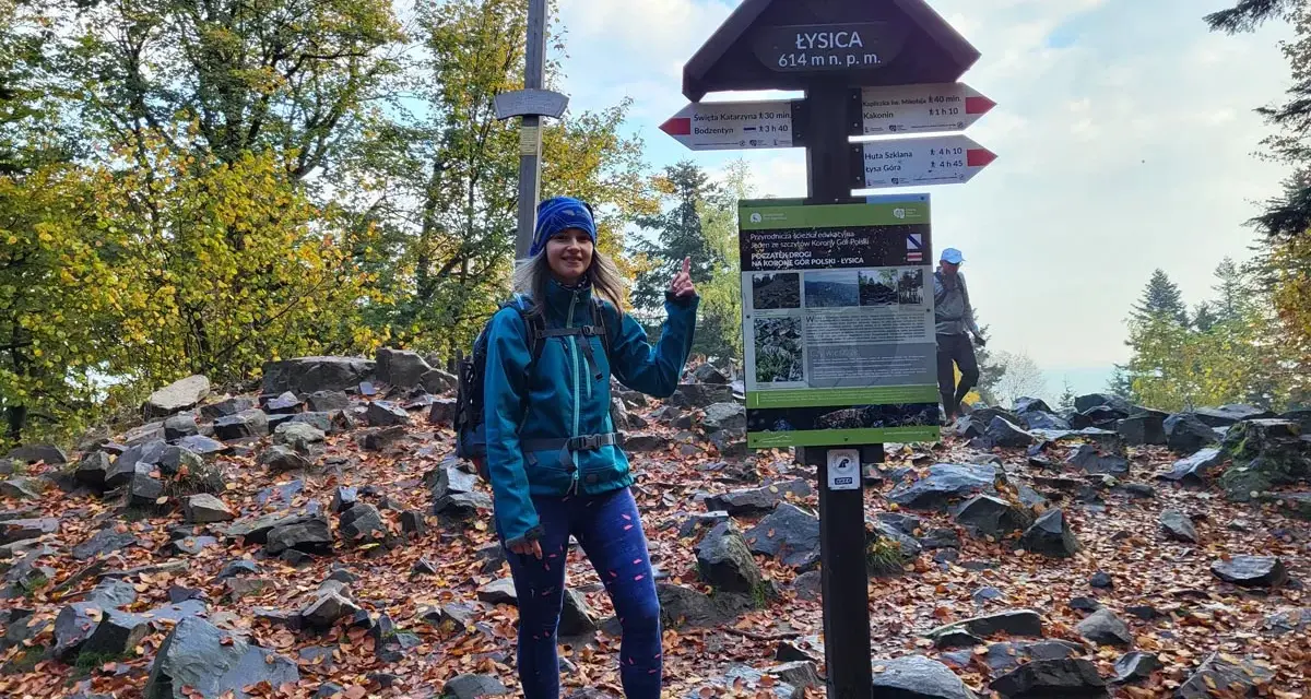 Kobieta na szczycie Łysicy, 614 m n.p.m., przy drogowskazie szlaku łysica - kakonin. Jesień w pełni, liście na ziemi.