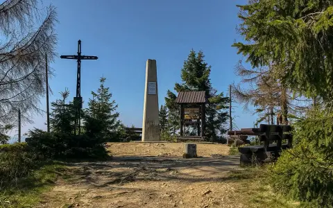 Na szczycie Turbacz, wśród **gorących szczytów**, stoi krzyż i obelisk. Wokół ławki i tablice informacyjne.