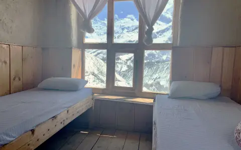 Pokój z dwoma łóżkami i widokiem na ośnieżone góry. Idealne miejsce na odpoczynek po trekkingu na Annapurna Circuit.