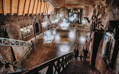 Rodzina schodzi schodami do podziemnej kaplicy w kopalni soli. Zwiedzanie Wieliczki to niezapomniane przeżycie.