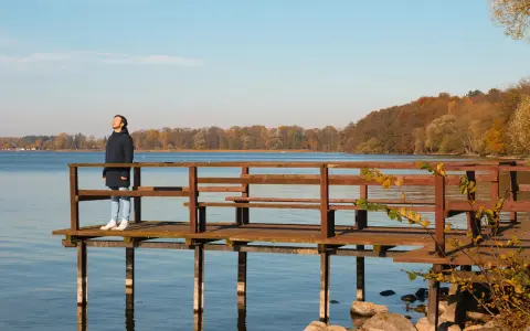 Mężczyzna na pomoście podziwia jesienne krajobrazy Pojezierza Drawskiego. To jedna z wielu pięknych atrakcji tego regionu.