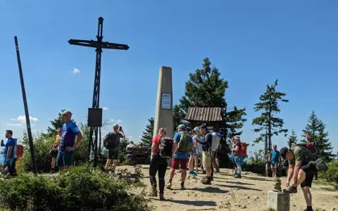 Grupa turystów na szczycie Turbacz z Koninek. Widoczny krzyż, pomnik i drewniana wiata.