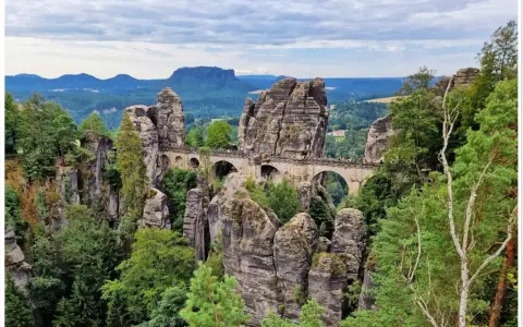 Kamienny most Bastei w Szwajcarskiej Saksonii, łączący skalne baszty pośród zielonych lasów i malowniczych gór.