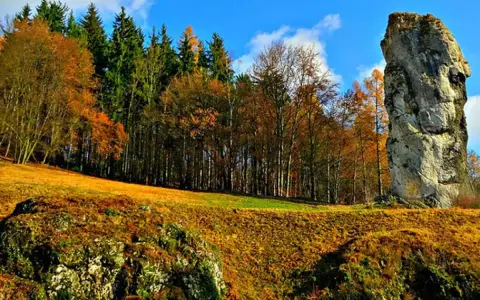 Maczuga Herkulesa na Jurze Krakowsko-Częstochowskiej. Jesienny krajobraz z dominującą skałą i kolorowym lasem.