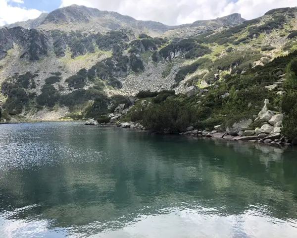 Spokojne jezioro odbija skaliste zbocza gór Pirin porośnięte kosodrzewiną.