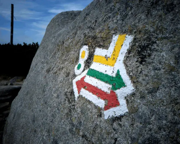 Kolorowe szlaki turystyczne (czerwony, zielony, żółty) namalowane na skale.
