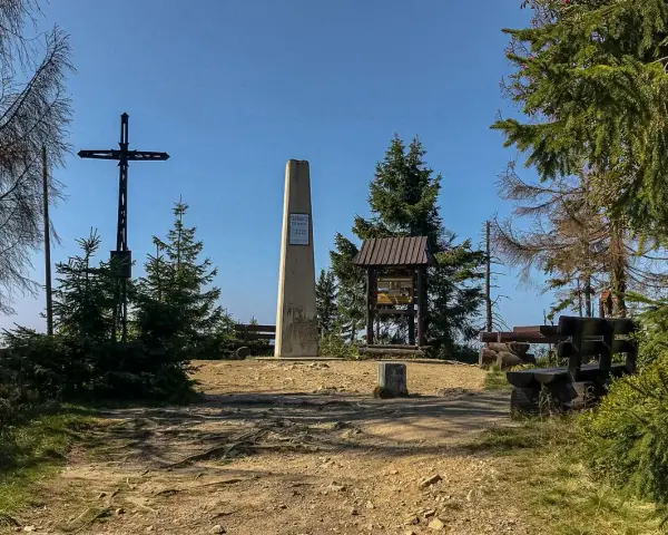 Na szczycie Turbacz, wśród **gorących szczytów**, stoi krzyż i obelisk. Wokół ławki i tablice informacyjne.