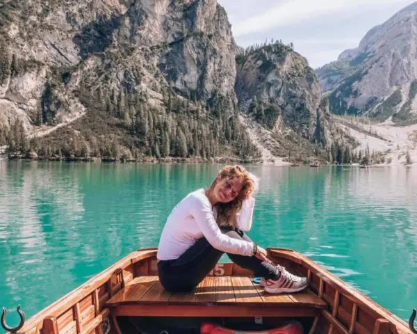 Kobieta w łodzi na turkusowym jeziorze w Dolomitach, w tle góry.