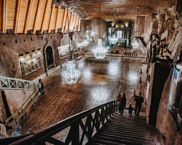 Rodzina schodzi schodami do podziemnej kaplicy w kopalni soli. Zwiedzanie Wieliczki to niezapomniane przeżycie.