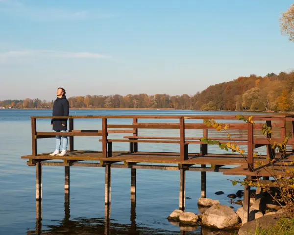Mężczyzna na pomoście podziwia jesienne krajobrazy Pojezierza Drawskiego. To jedna z wielu pięknych atrakcji tego regionu.