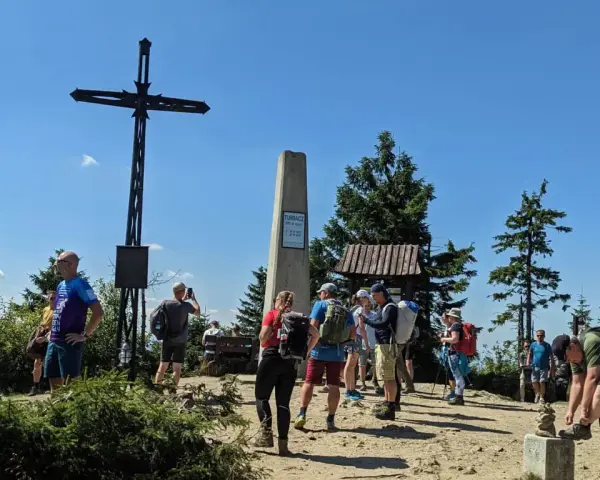 Grupa turystów na szczycie Turbacz z Koninek. Widoczny krzyż, pomnik i drewniana wiata.