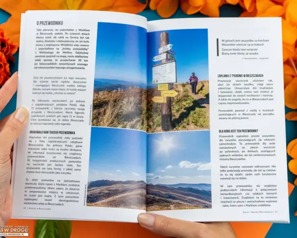 Widok na malownicze **Bieszczady** z połonin. Na pierwszym planie drogowskazy, w tle turystka.