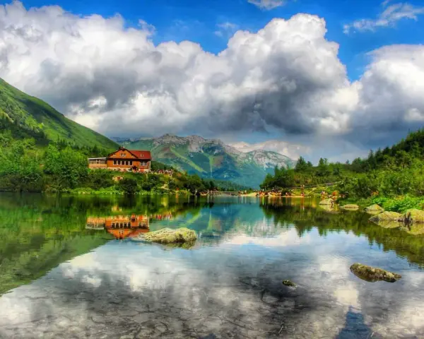 Słowackie Tatry zachwycają. Jezioro z odbiciem chatki i gór to idealne miejsce na tatry słowackie szlaki z dzieckiem.