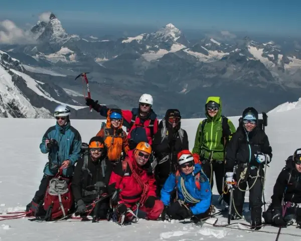 Grupa alpinistów na tle majestatycznego Monte Rosa, gotowa do zdobycia szczytu.