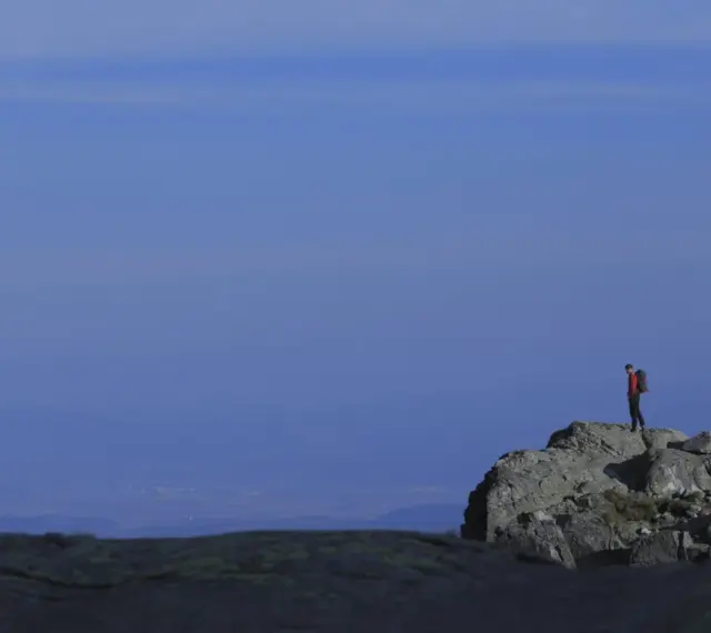 Turysta na skalistym szczycie, podziwiający widok. Tatry oferują wiele łatwych szczytów dla miłośników gór.