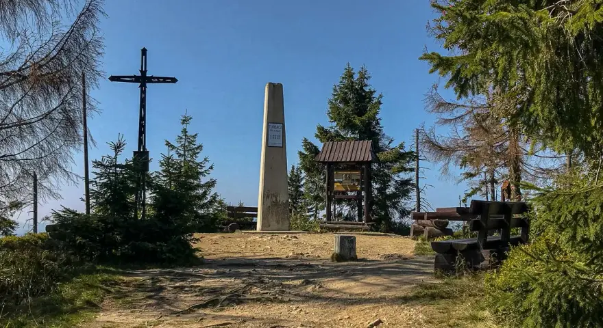 Na szczycie Turbacz, wśród **gorących szczytów**, stoi krzyż i obelisk. Wokół ławki i tablice informacyjne.
