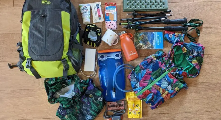 Plecak, kijki trekkingowe, bukłak, kurtka przeciwdeszczowa i inne niezbędne przedmioty tworzą kompletny ekwipunek w góry.