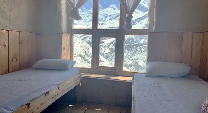 Pokój z dwoma łóżkami i widokiem na ośnieżone góry. Idealne miejsce na odpoczynek po trekkingu na Annapurna Circuit.