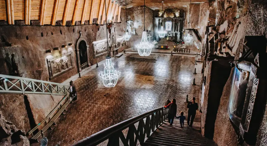 Rodzina schodzi schodami do podziemnej kaplicy w kopalni soli. Zwiedzanie Wieliczki to niezapomniane przeżycie.
