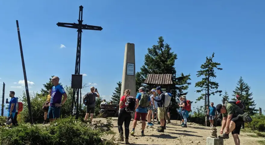 Grupa turystów na szczycie Turbacz z Koninek. Widoczny krzyż, pomnik i drewniana wiata.