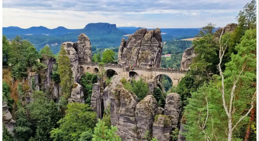 Kamienny most Bastei w Szwajcarskiej Saksonii, łączący skalne baszty pośród zielonych lasów i malowniczych gór.