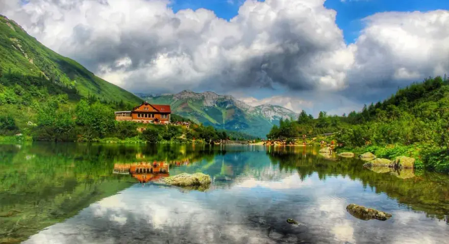 Słowackie Tatry zachwycają. Jezioro z odbiciem chatki i gór to idealne miejsce na tatry słowackie szlaki z dzieckiem.