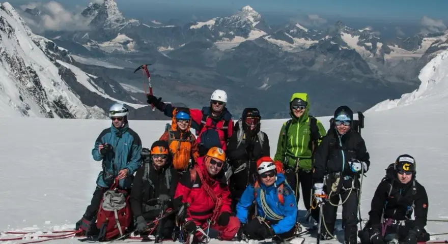 Grupa alpinistów na tle majestatycznego Monte Rosa, gotowa do zdobycia szczytu.