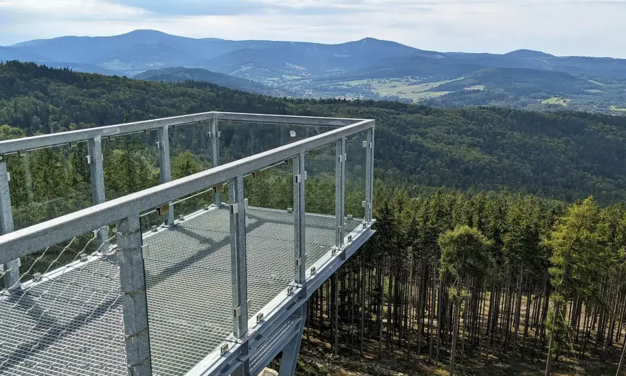 Widok z platformy widokowej na gęsty las i góry. To idealne miejsce, by poczuć się jak ptak i zobaczyć, jak wejść na Trojak.