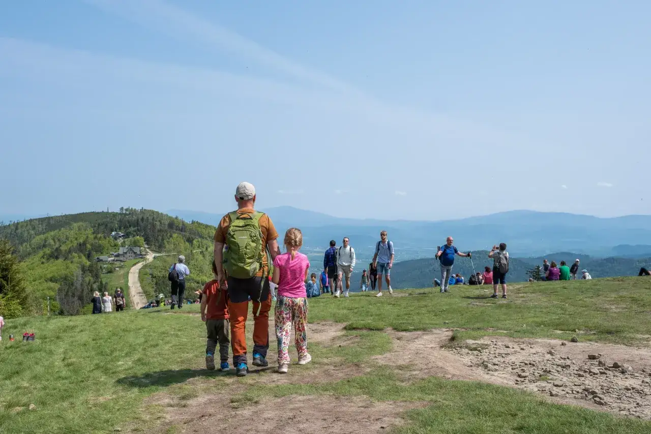 Rodzina na szczycie Klimczoka. Ojciec z dzieckiem podziwiają widok na Beskidy.