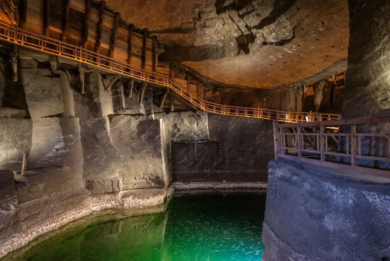 Podziemny korytarz z drewnianymi balustradami i zielonym jeziorem solankowym. Zwiedzanie Wieliczki trwa ok. 3 godzin.